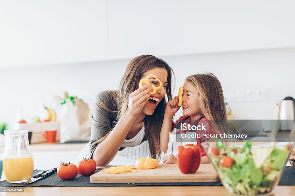 mother and daughter having fun with the vegetables in the kitchen.